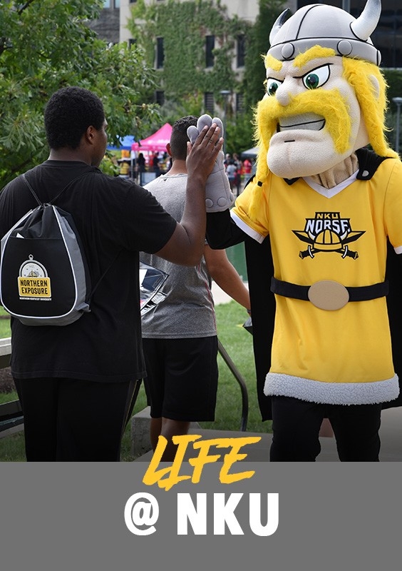 Life at ɫƬ: Student at an event giving Victor E. Viking a high-five
